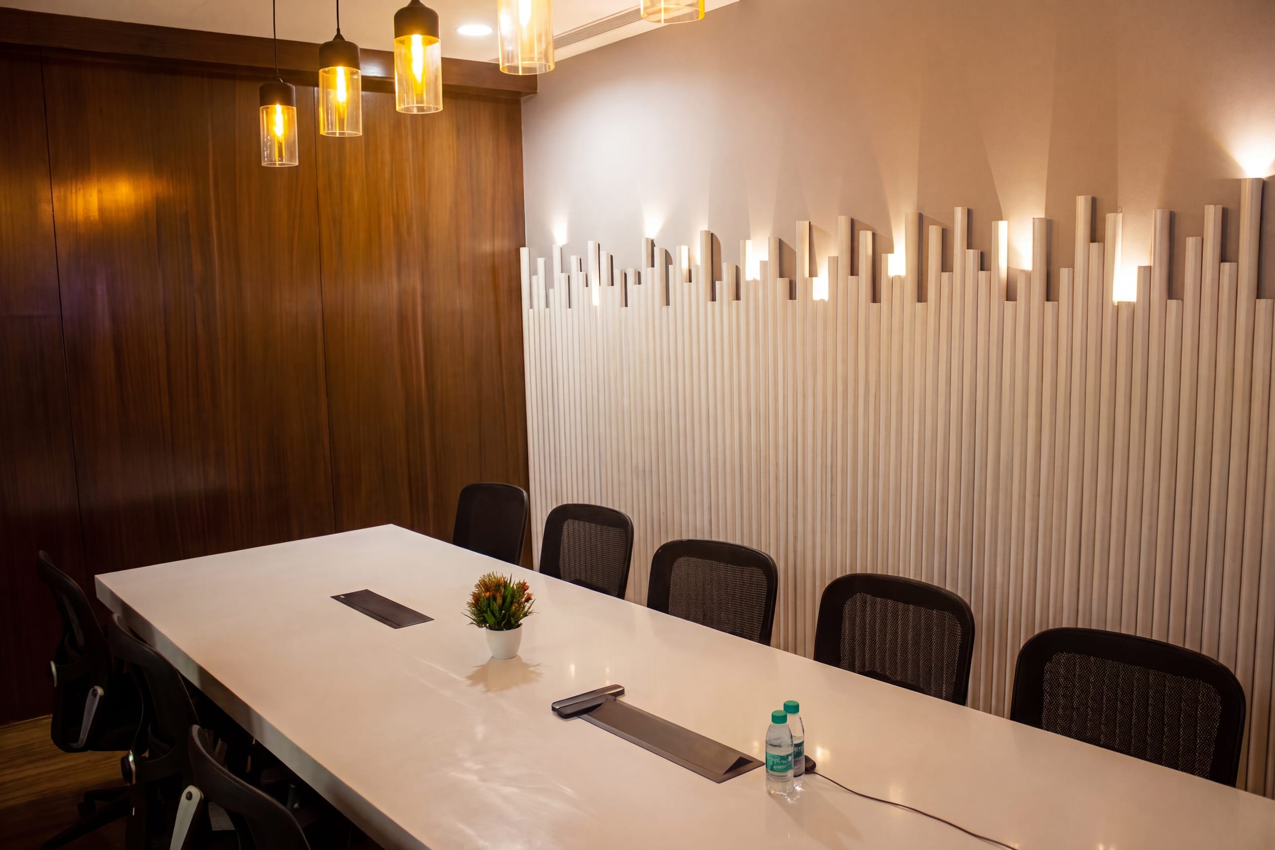 Conference room with exposed pipe lighting and raw feature wall at Flock office