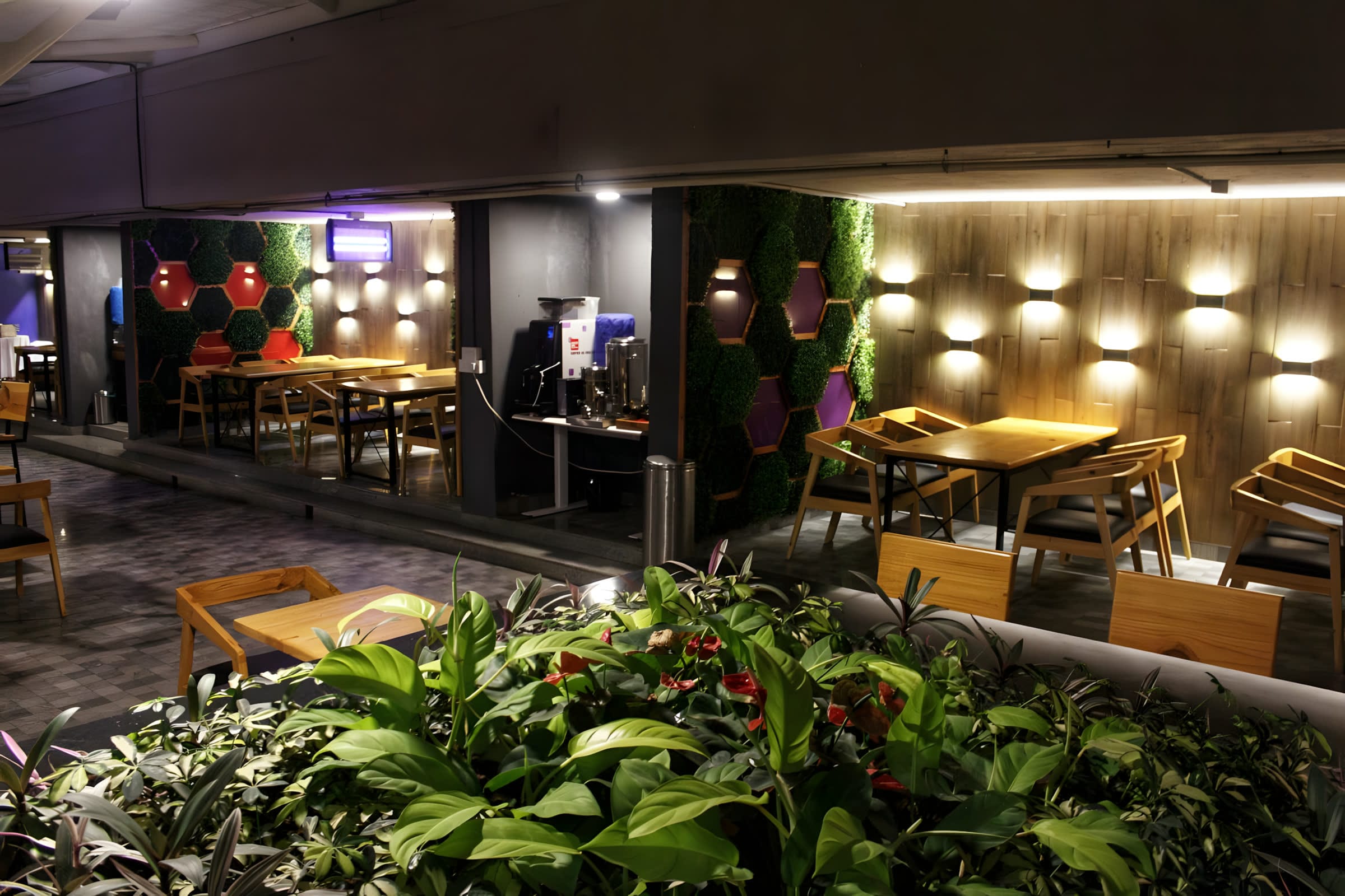 Cafeteria with timber tables and a green moss feature wall at Flock office