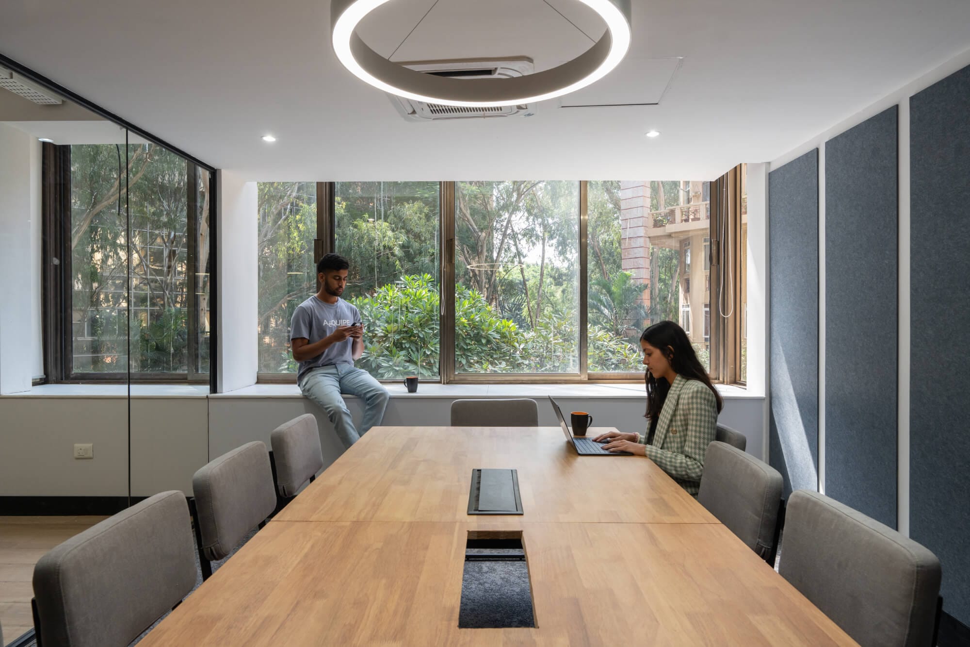 Glass-walled meeting room with timber table and garden view at the MOSS Golden Enclave office