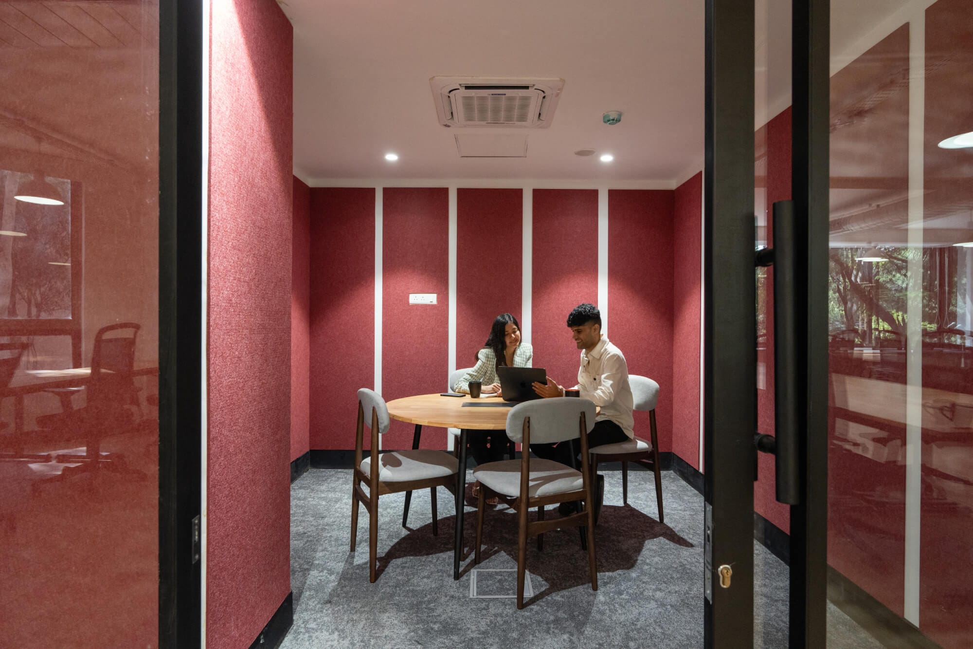 Deep-red glass-walled meeting room at the MOSS Golden Enclave office