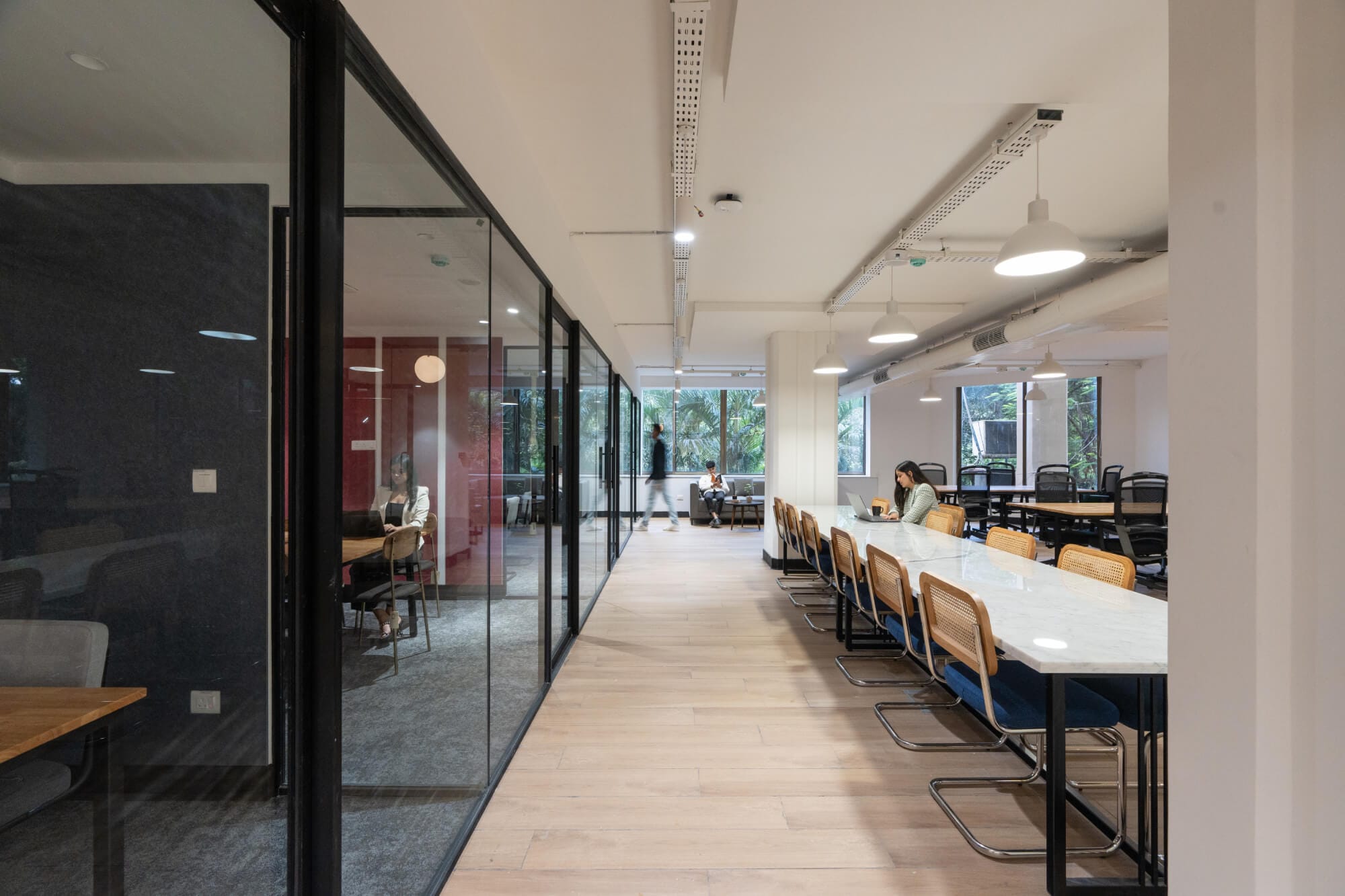 Workstations beside a glass-walled meeting room at the MOSS Golden Enclave office