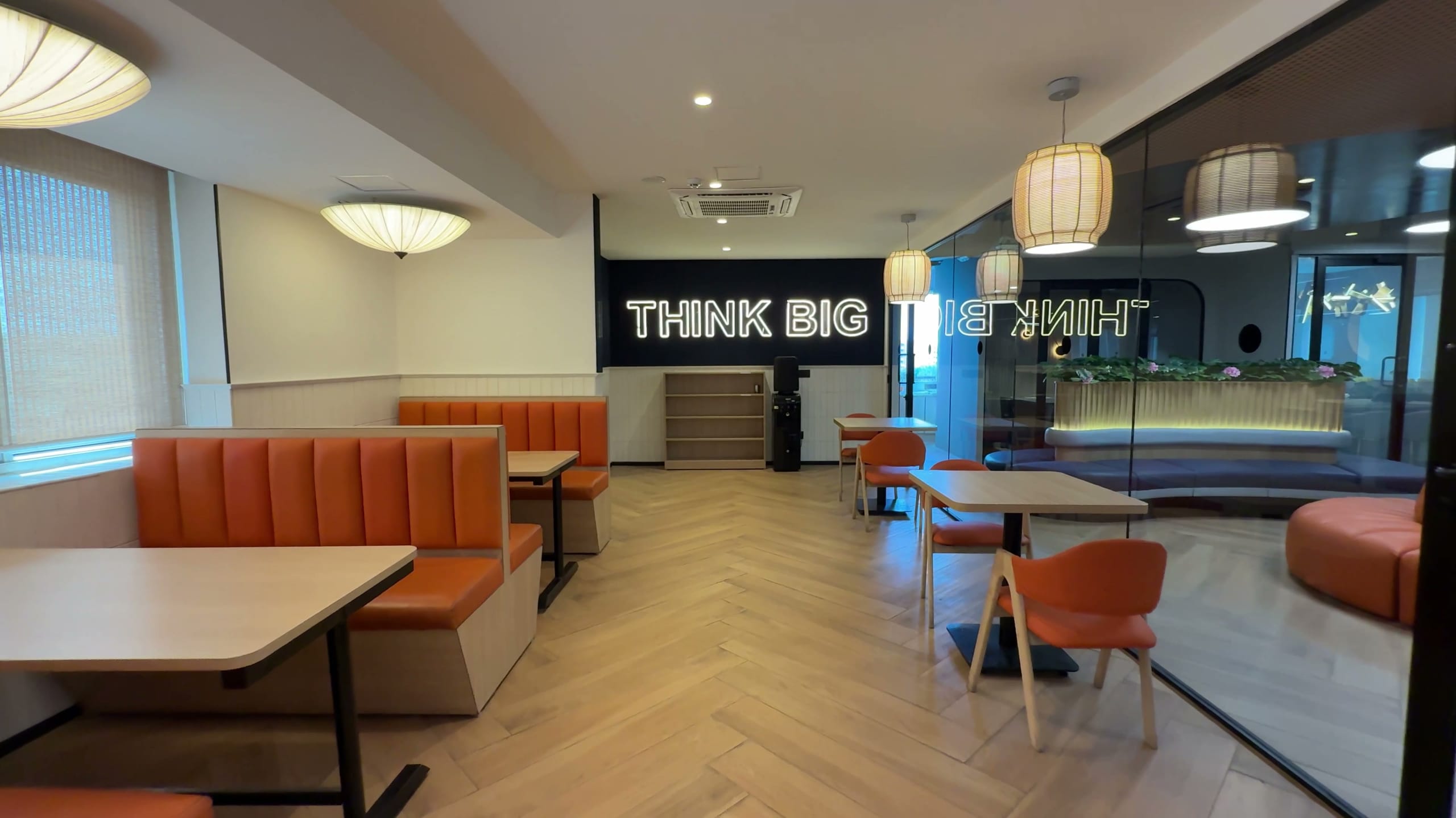 Office cafeteria with booth seating and "Think Big" signage, Rugr office