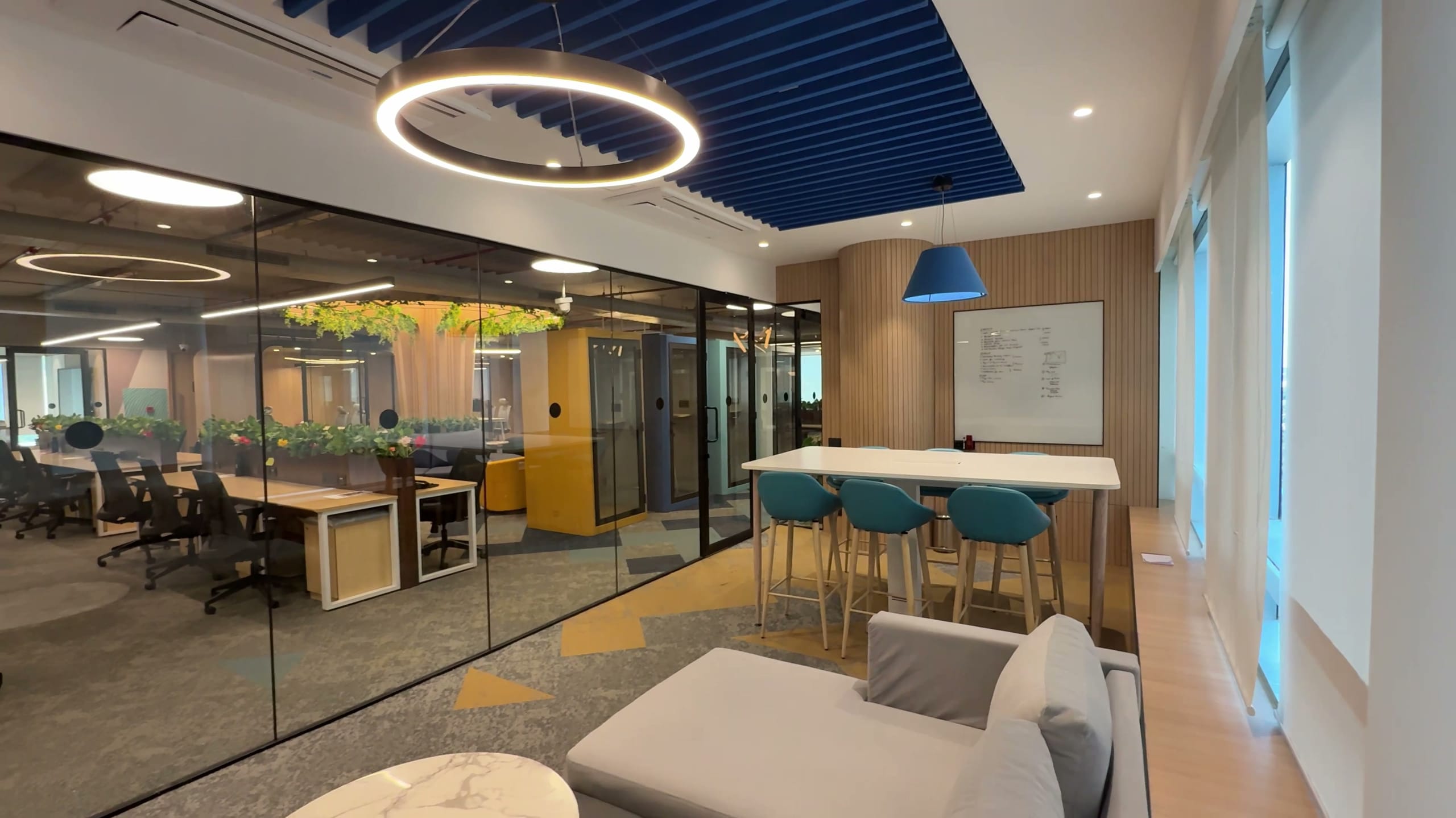 Glass-walled meeting room beside open workstations, Rugr office