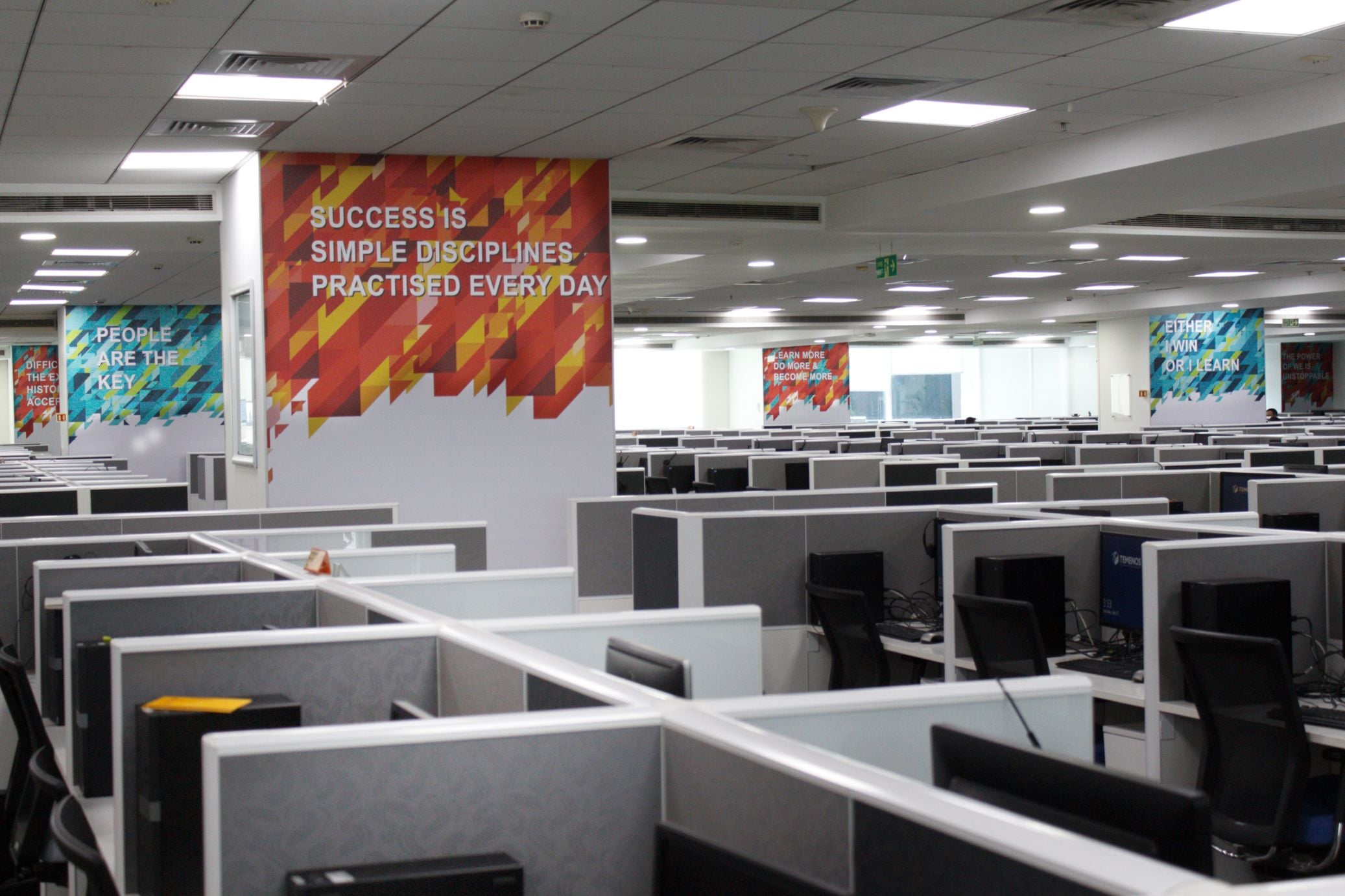 Workstations beside a graphic quote wall at Temenos office