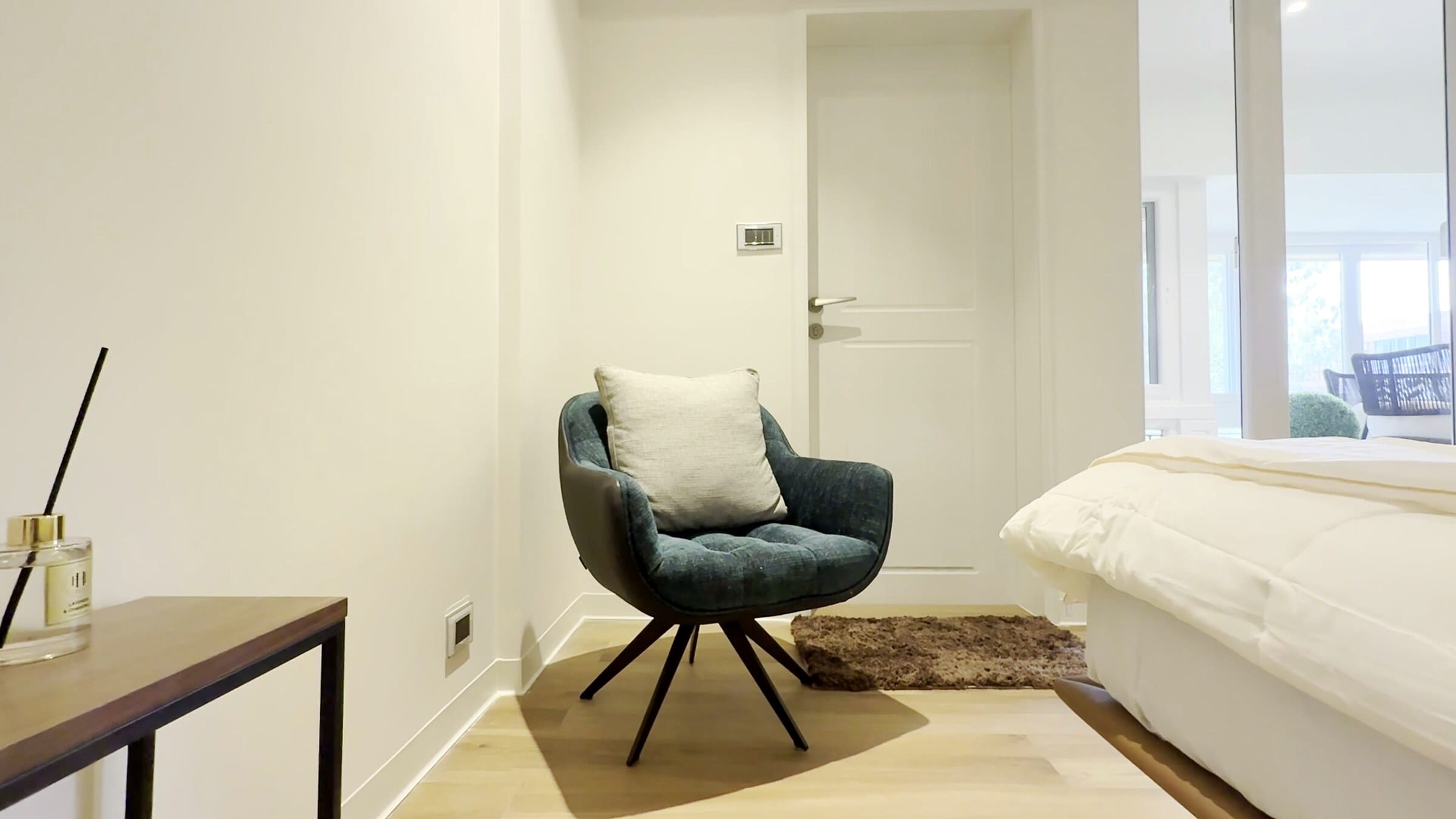 Second bedroom with turquoise accent chair at the Golden Enclave flat